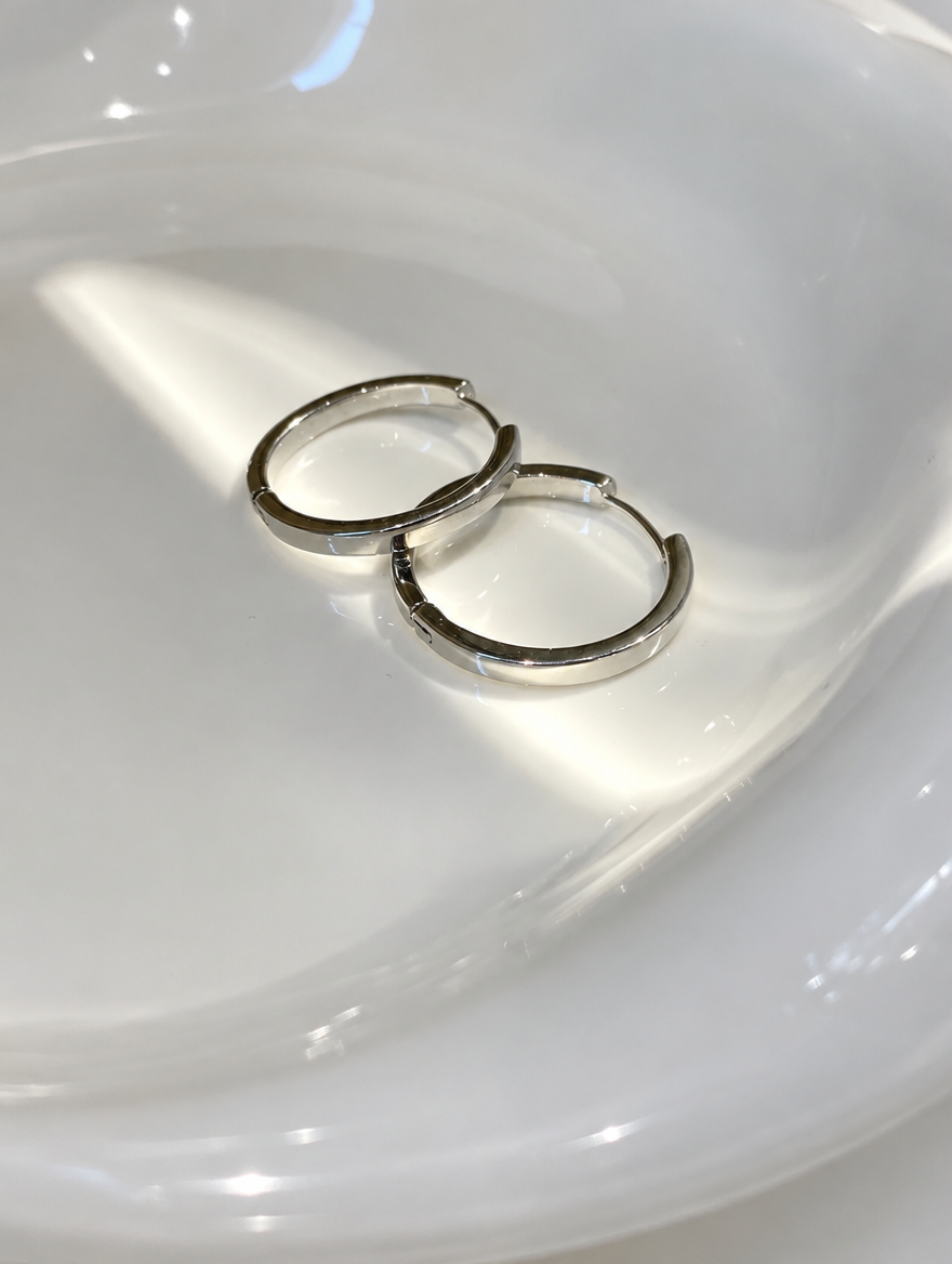Classic silver-tone round hoop earrings lying flat on a soft styled surface