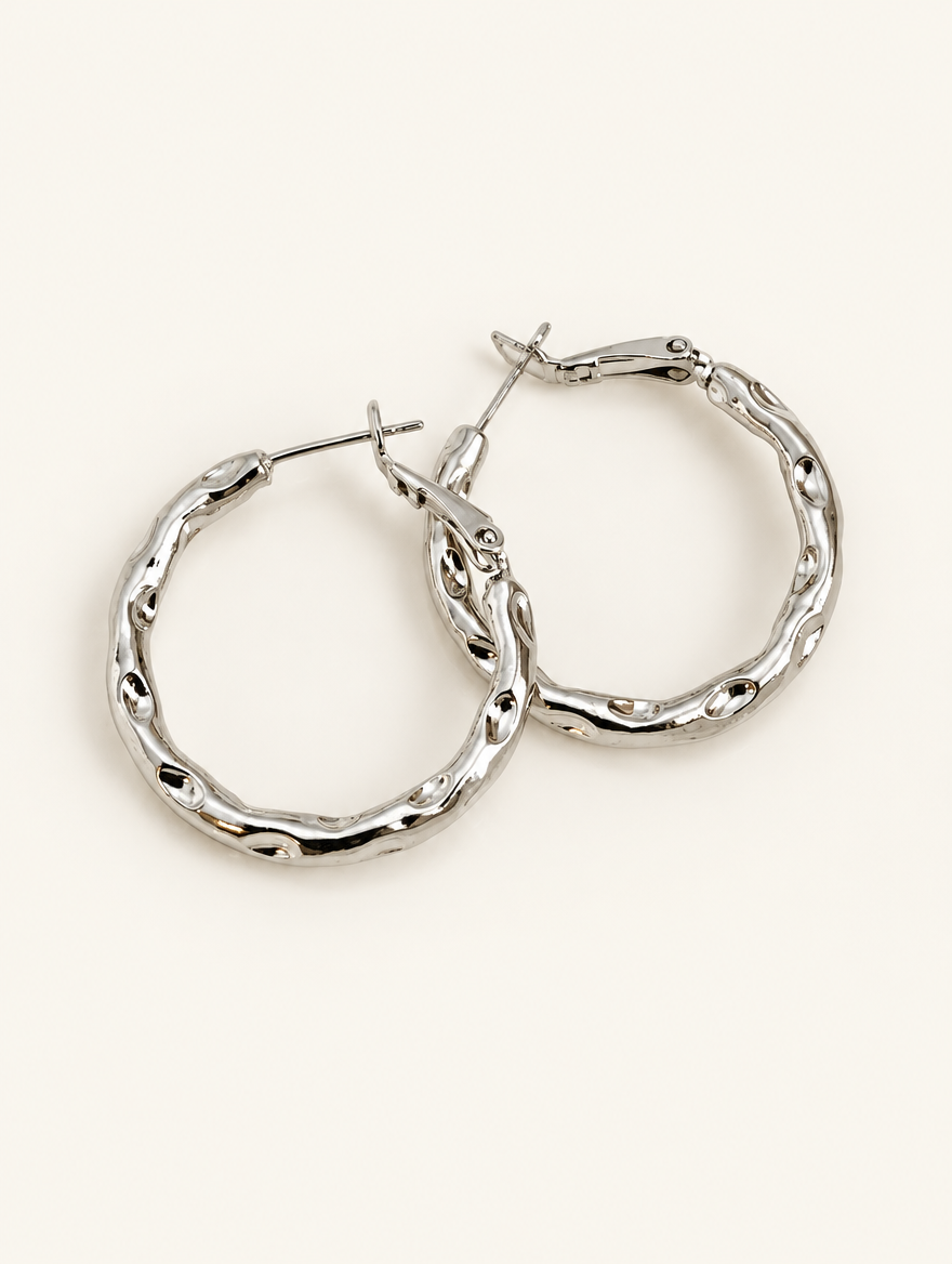 Pair of silver-tone textured twisted hoop earrings on a warm off-white background