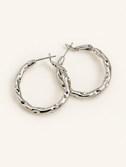 Pair of silver-tone textured twisted hoop earrings on a warm off-white background