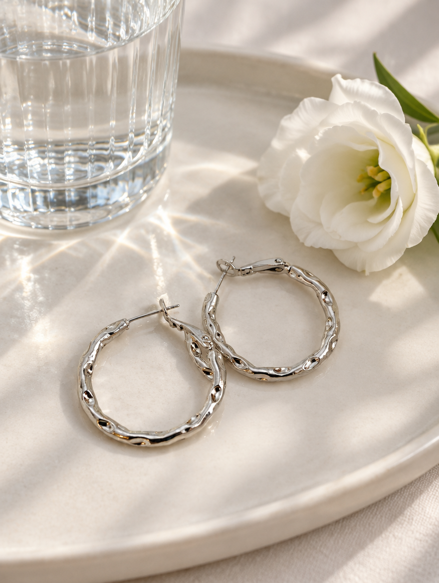 Silver-tone textured twisted hoop earrings in a styled still life with props