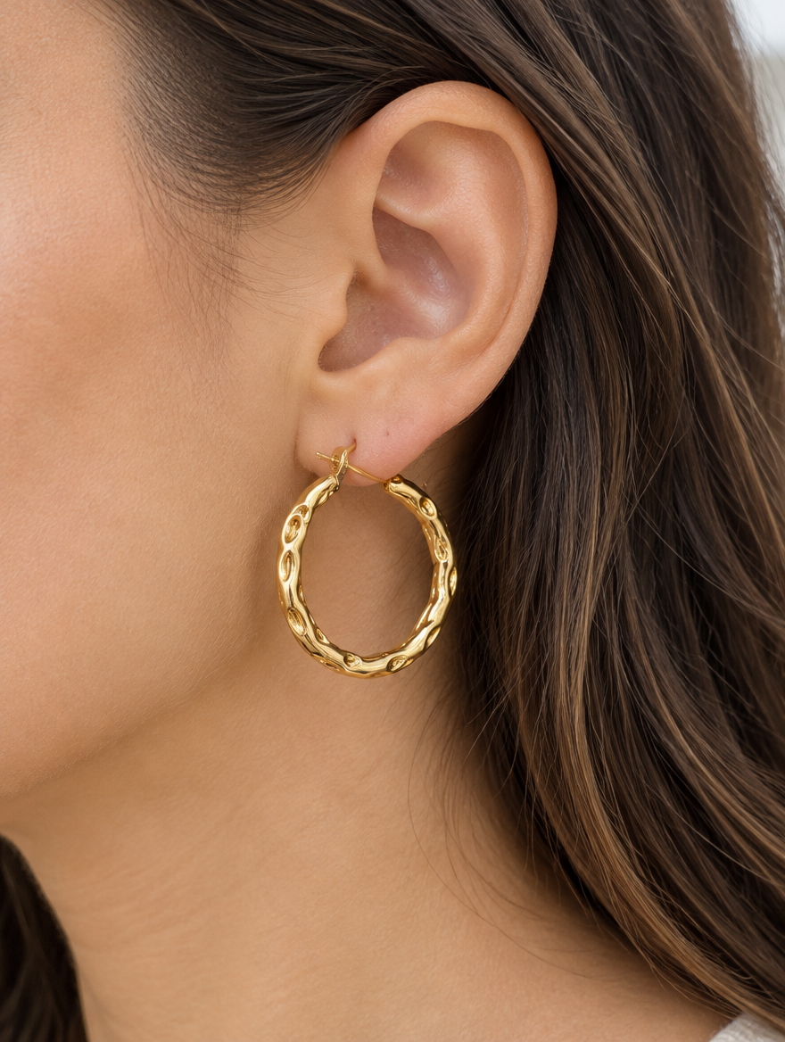 Woman wearing a gold-tone textured twisted hoop earring