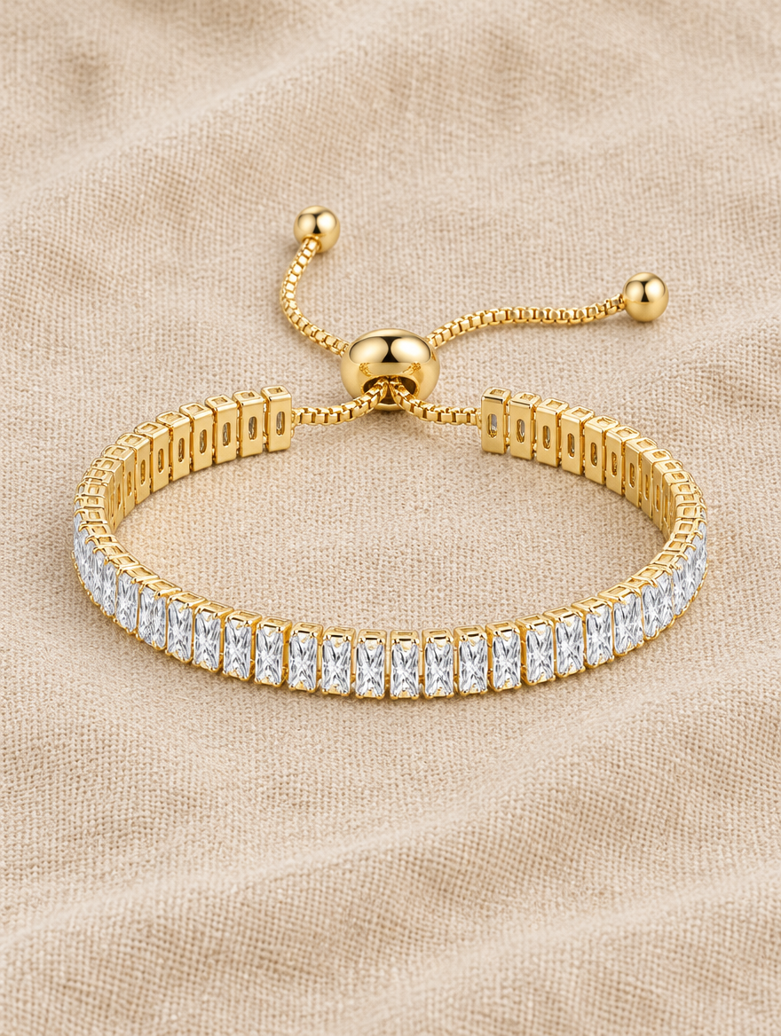 Gold slider tennis bracelet with two rows of stones on beige linen