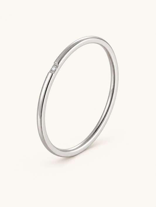 Thin silver stacking ring with a single zirconia on a neutral background