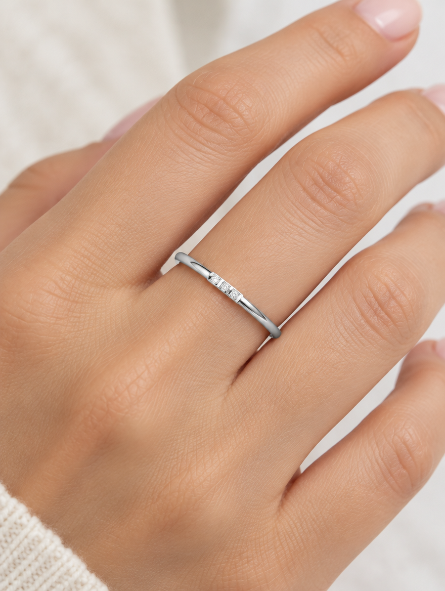 Woman wearing a thin silver stacking ring with three zirconia stones on her finger