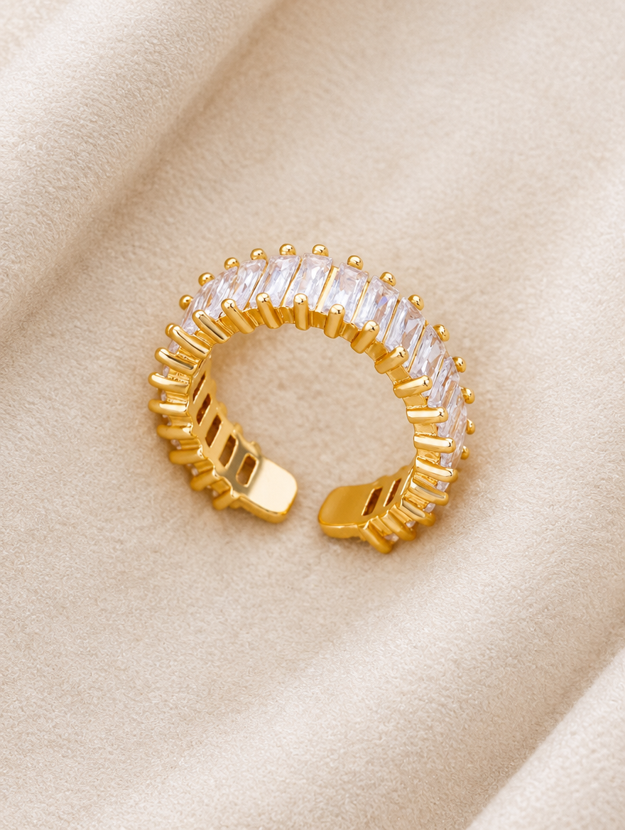 Gold baguette clear stone ring resting on a soft textured surface