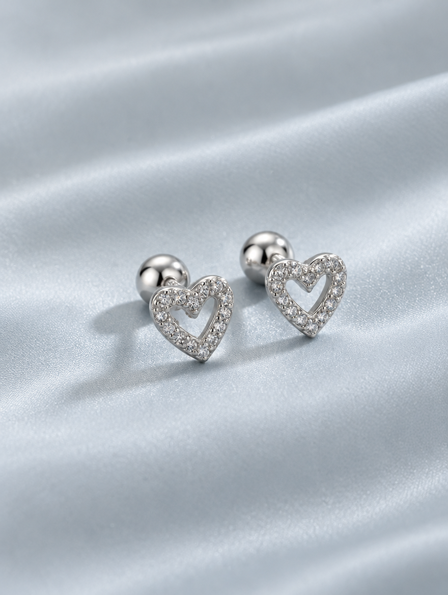Silver open heart stud earrings lying flat on a soft styled surface