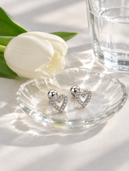 Silver open heart stud earrings in a styled still life with props