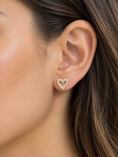 Woman wearing a gold open heart stud earring