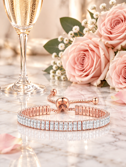 Rose gold slider bracelet beside a champagne flute and a blush rose on marble