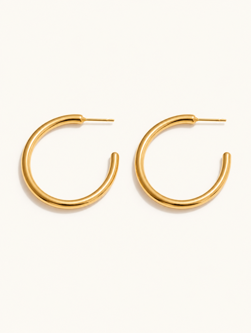 Pair of gold open c-shape hoop earrings on a warm off-white background