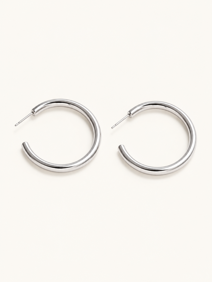 Pair of silver open c-shape hoop earrings on a warm off-white background