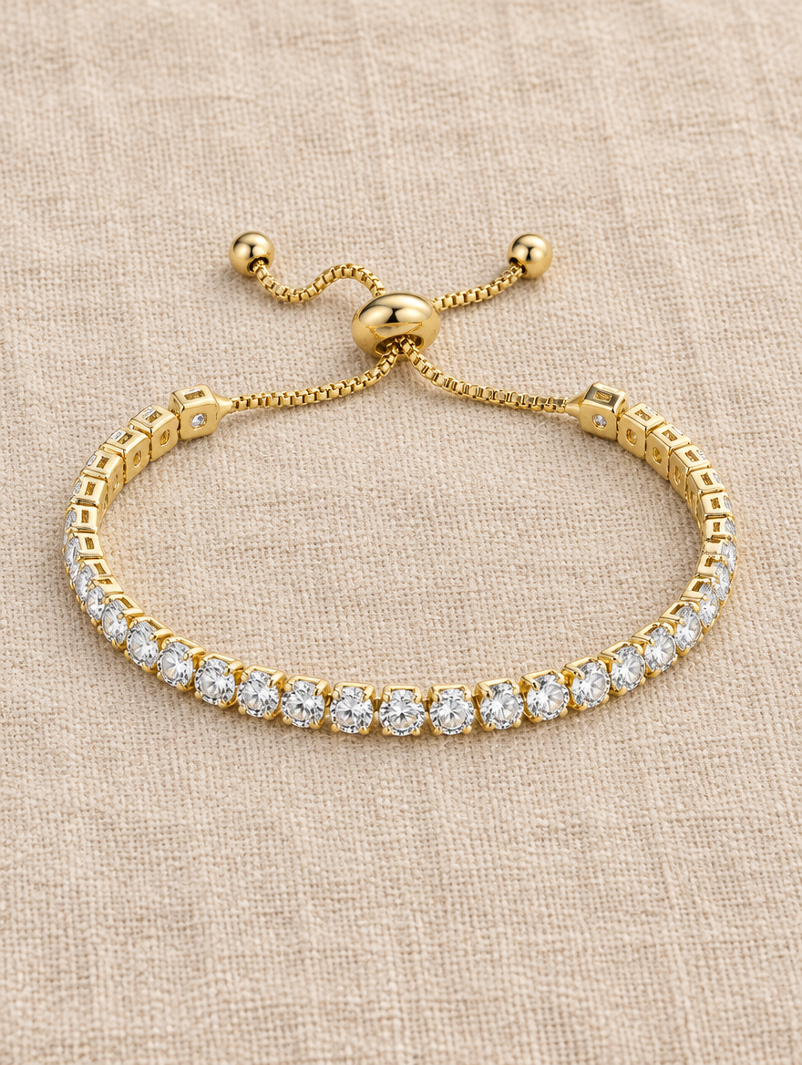 Gold slider tennis bracelet with round stones on beige linen