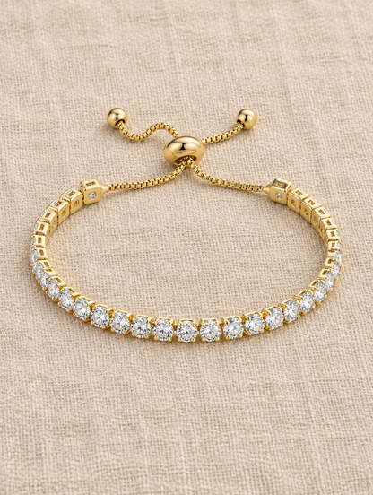 Gold slider tennis bracelet with round stones on beige linen