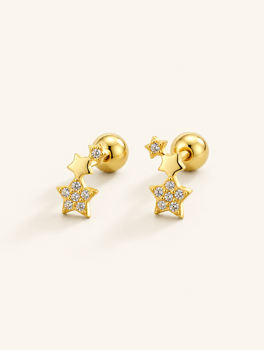Pair of gold star stud earrings on a warm off-white background