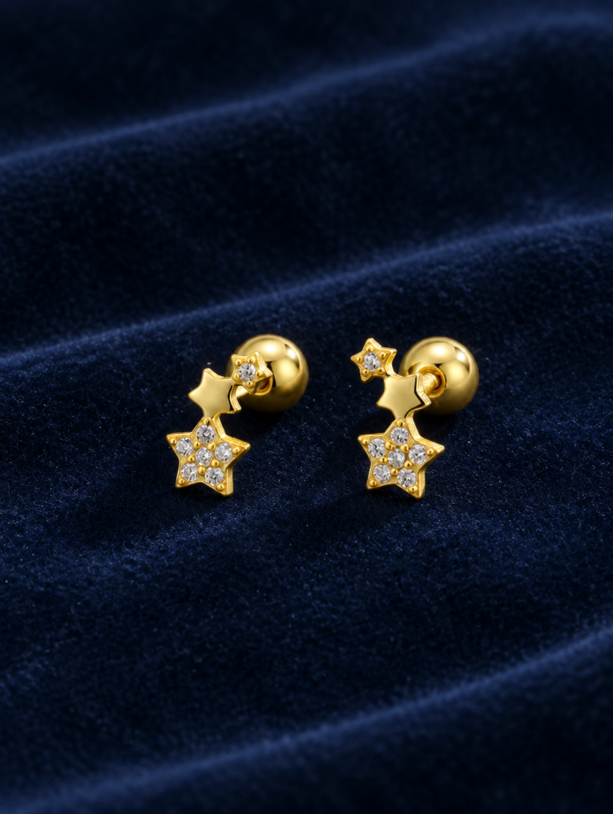 Gold star stud earrings lying flat on a soft styled surface