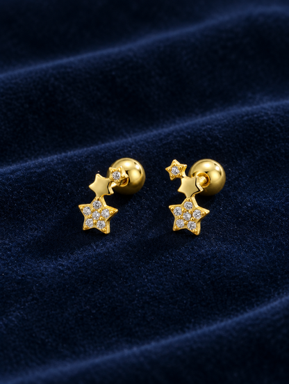 Gold star stud earrings lying flat on a soft styled surface