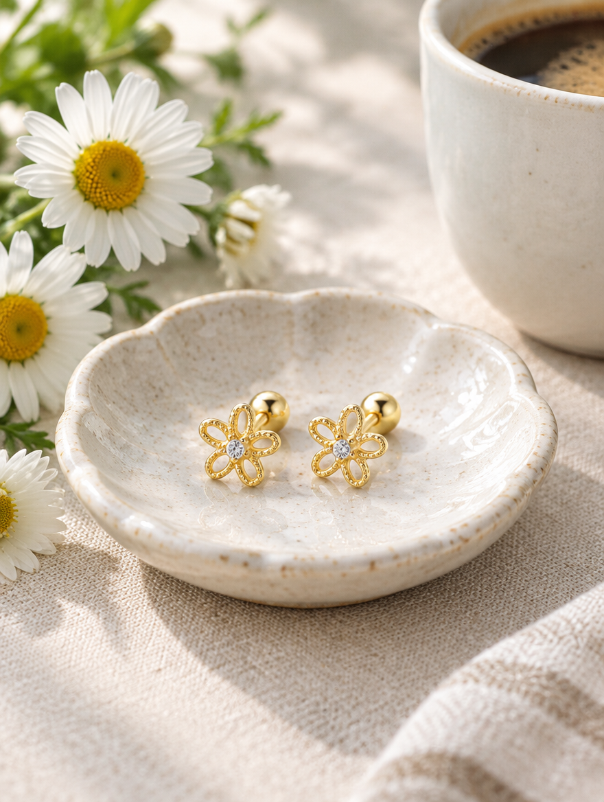 Gold flower stud earrings in a styled still life with props
