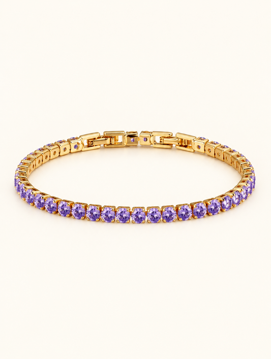 Gold tennis bracelet with purple zirconia stones on a neutral background