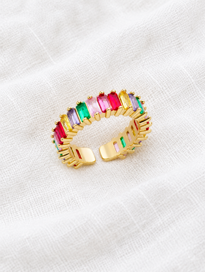 Gold rainbow baguette stone ring resting on a soft textured surface