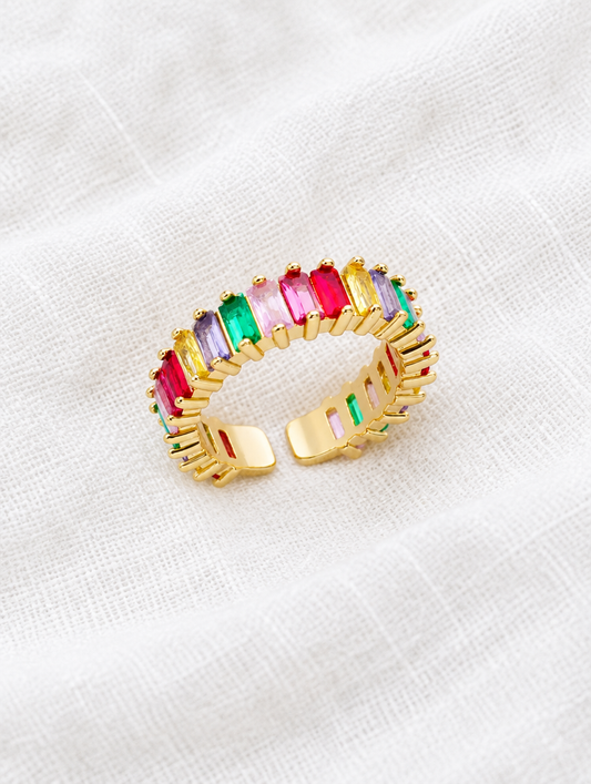 Gold rainbow baguette stone ring resting on a soft textured surface