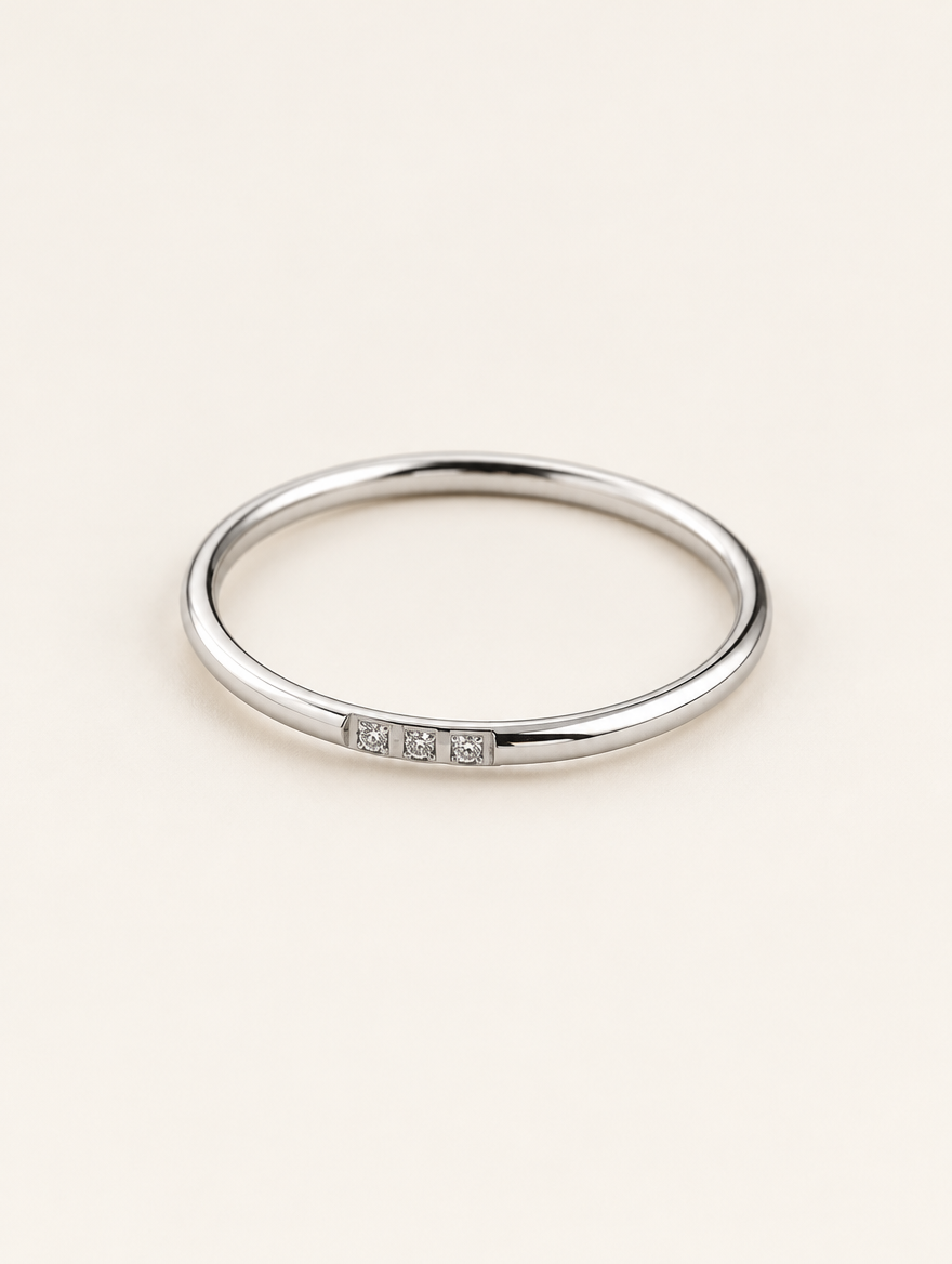 Thin silver stacking ring with three zirconia stones on a neutral background