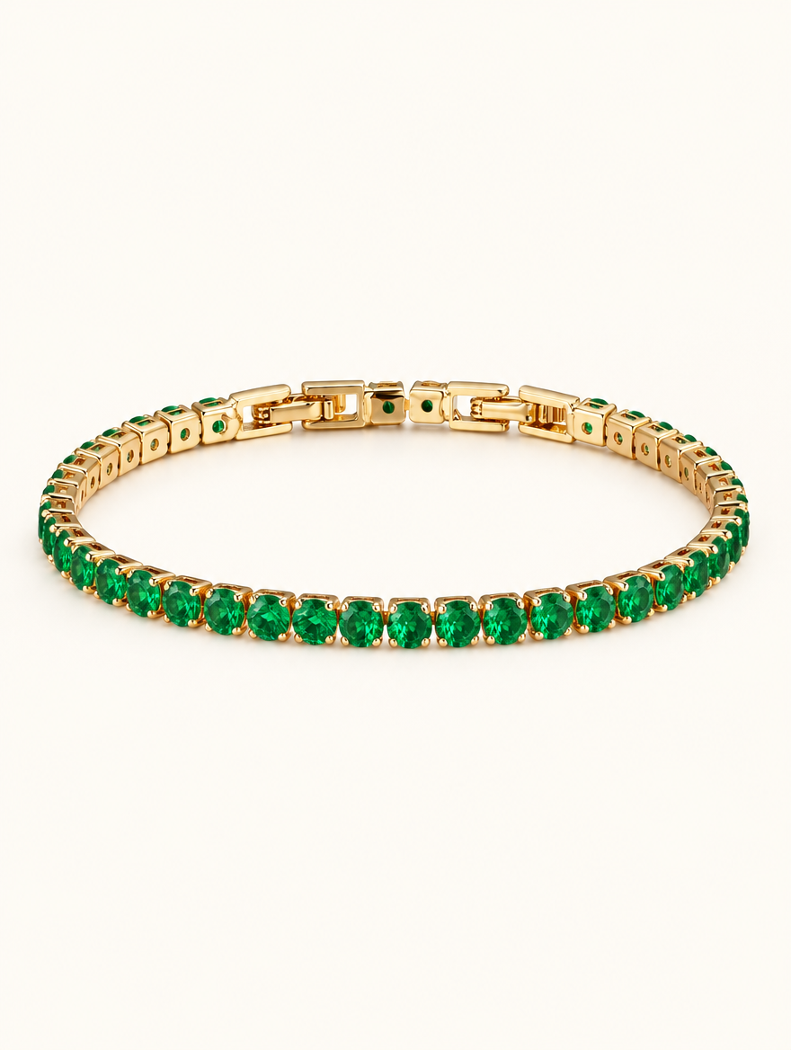 Gold tennis bracelet with emerald green zirconia stones on a neutral background