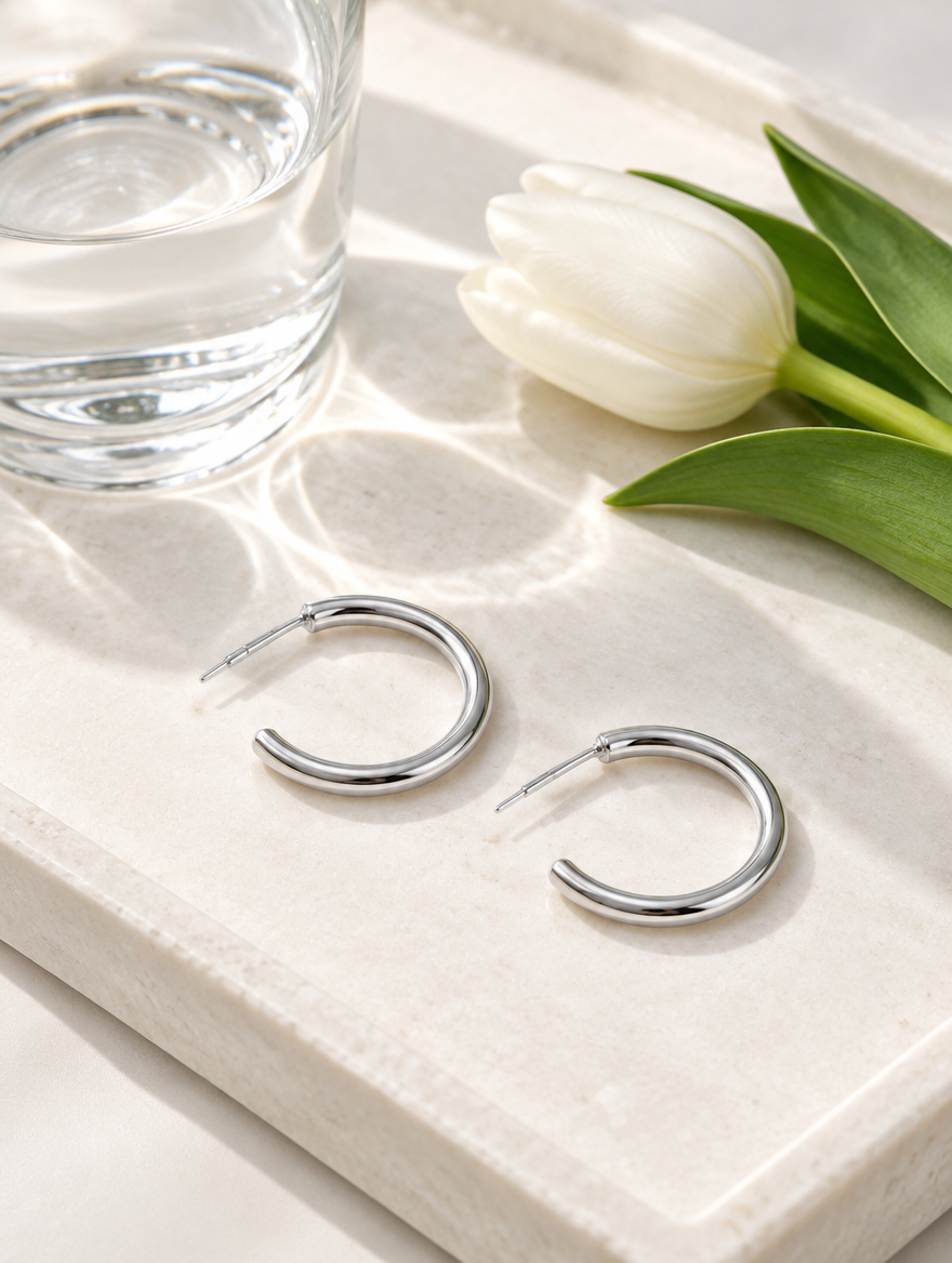 Silver open c-shape hoop earrings in a styled still life with props