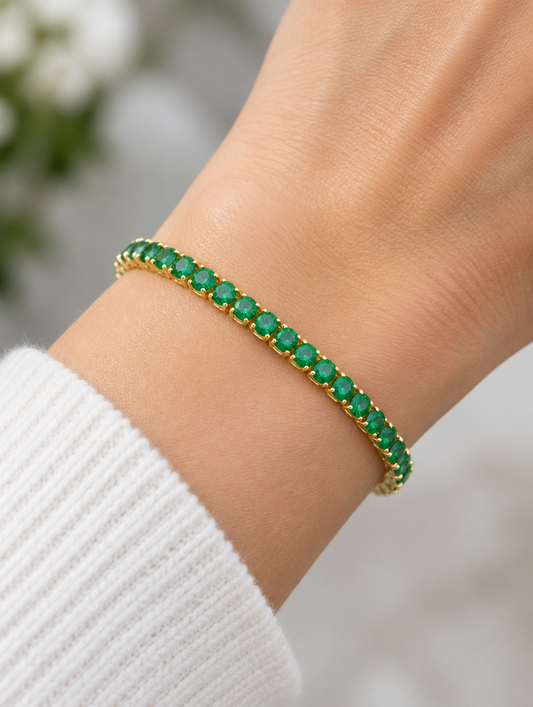 Woman wearing a gold tennis bracelet with emerald green zirconia stones