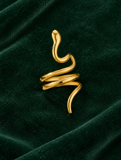 Gold snake coil ring resting on a soft textured surface