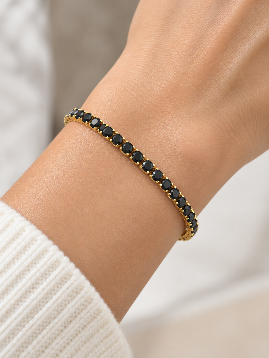 Woman wearing a gold tennis bracelet with black zirconia stones