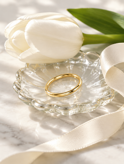 Thin gold polished band ring in a small dish with styling props