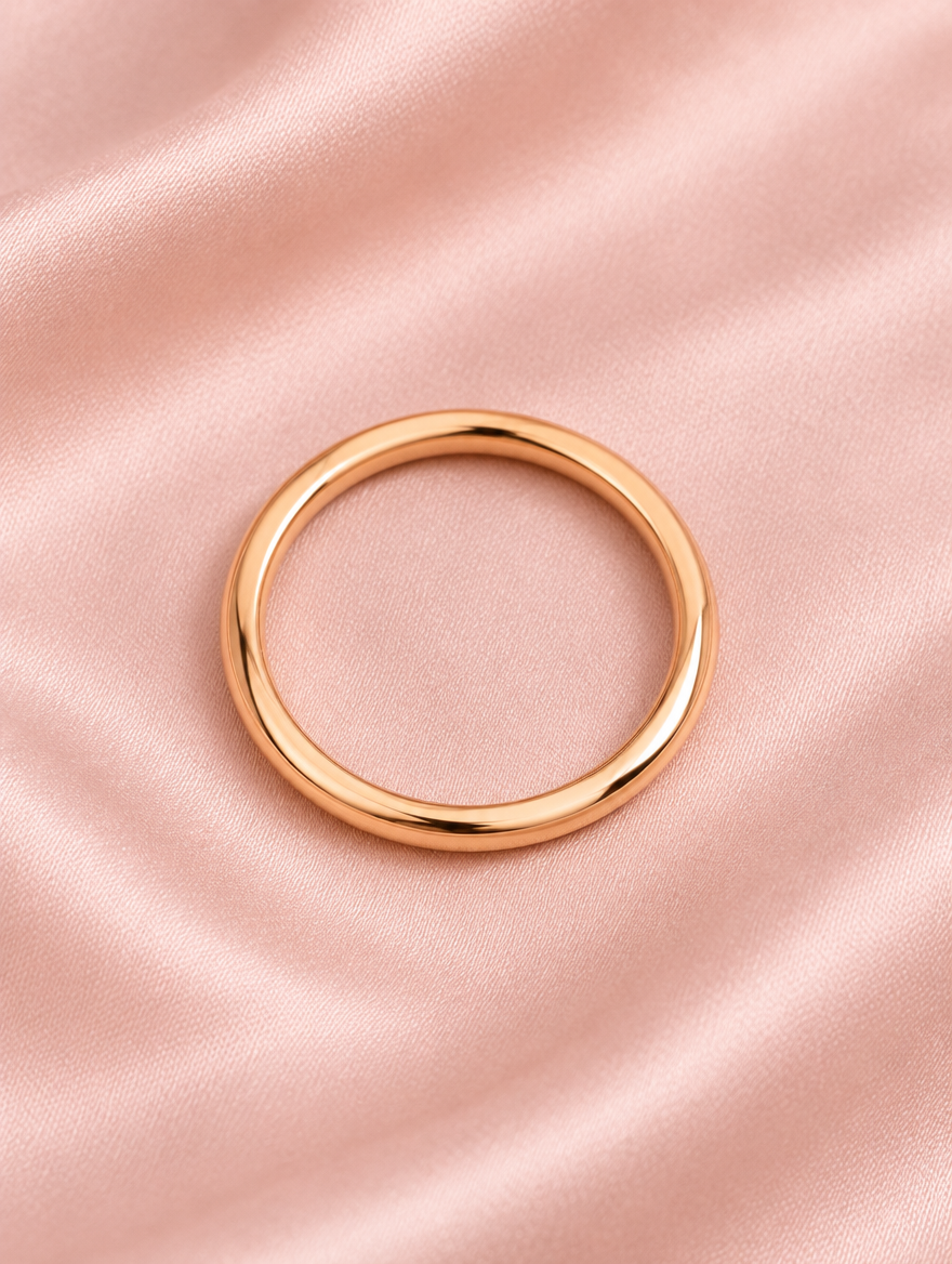 Thin rose gold polished band ring resting on a soft textured surface