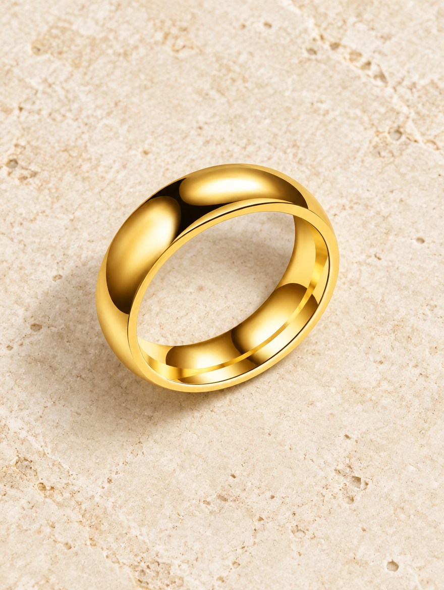 Wide gold domed polished band ring resting on a soft textured surface
