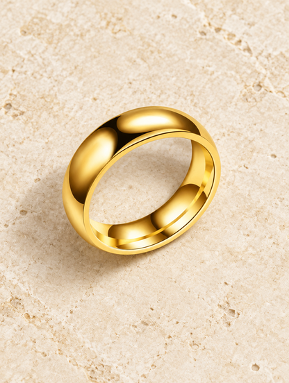 Wide gold domed polished band ring resting on a soft textured surface