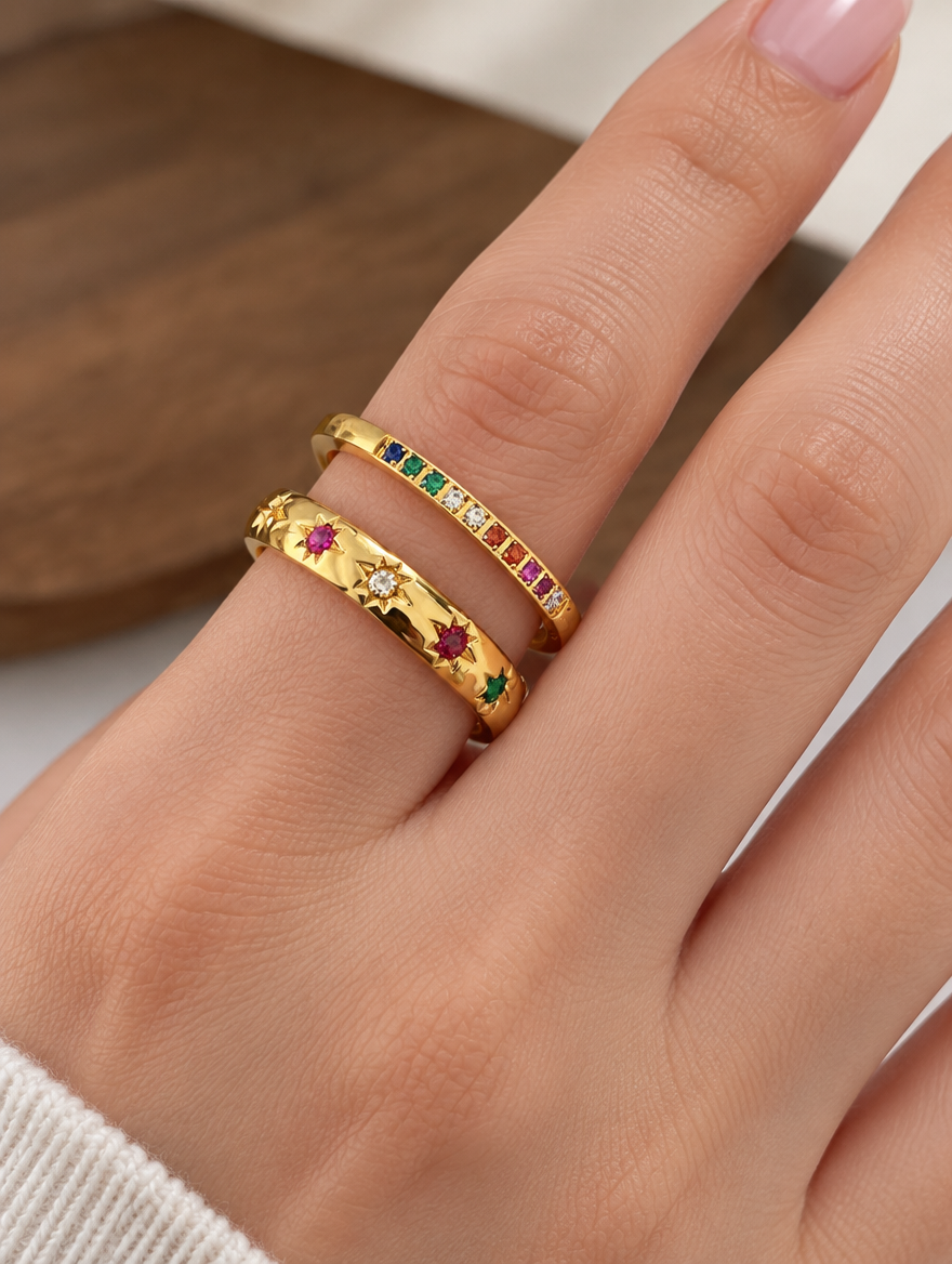 Woman wearing a set of two gold rainbow zirconia and star rings on her finger