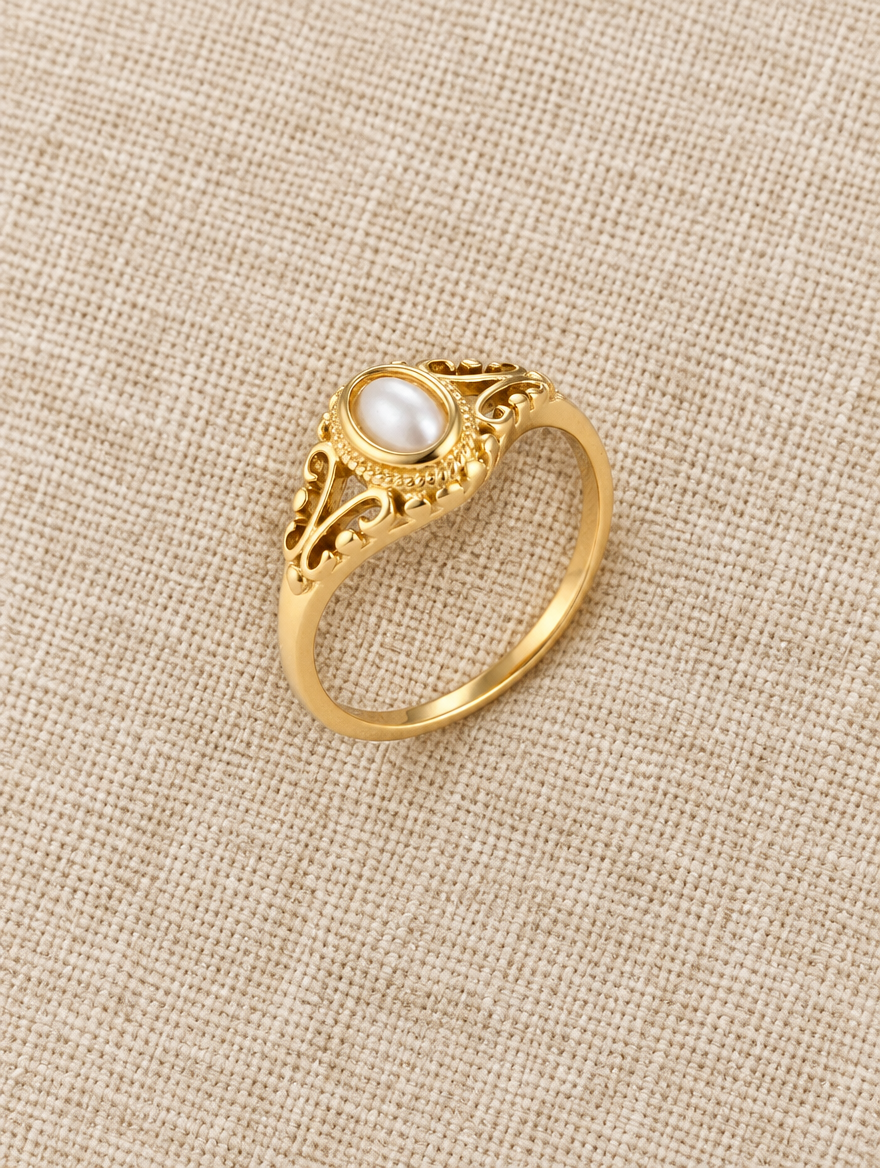 Gold vintage-style pearl ring resting on a soft textured surface