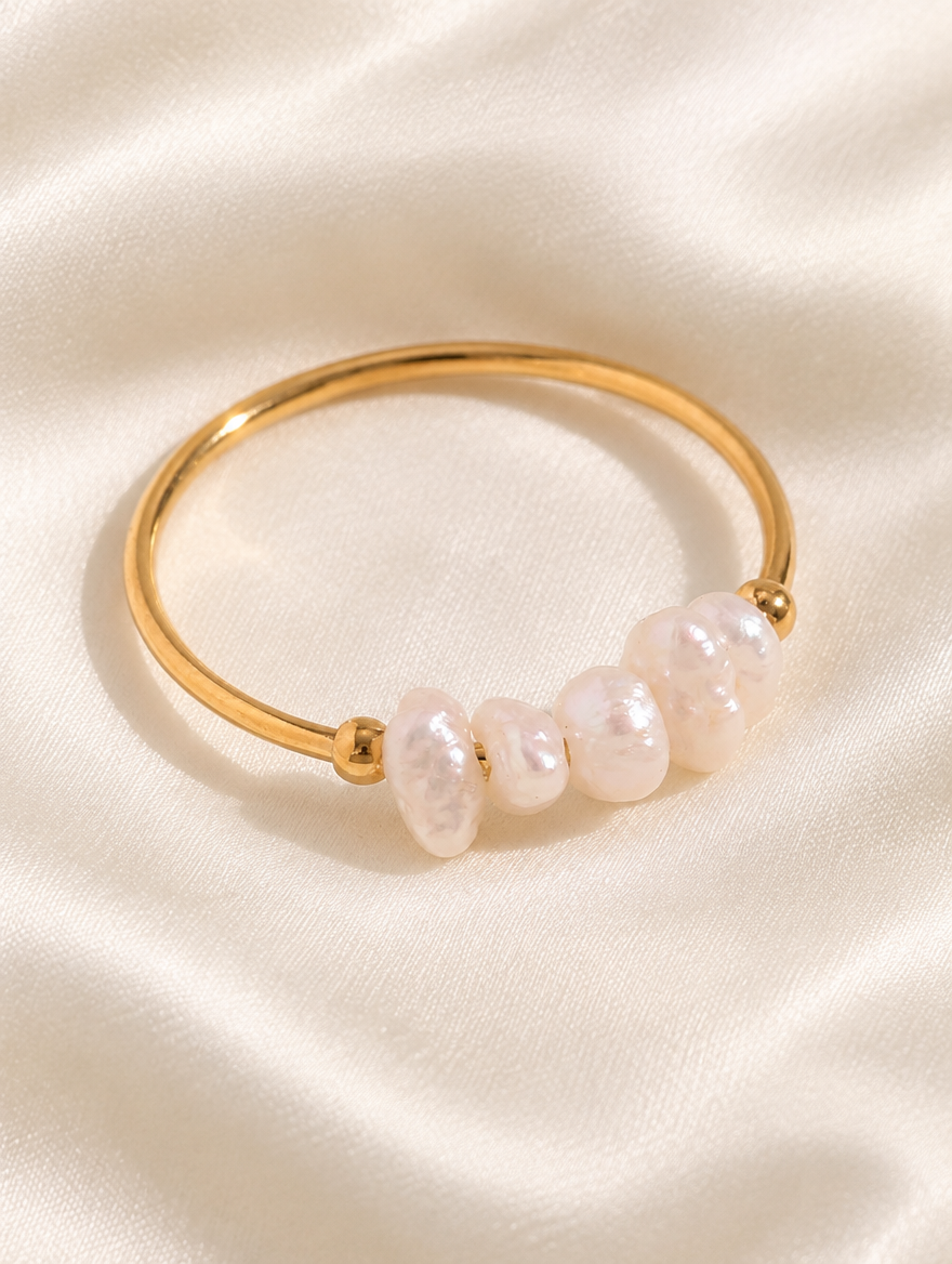Gold freshwater pearl open ring resting on a soft textured surface