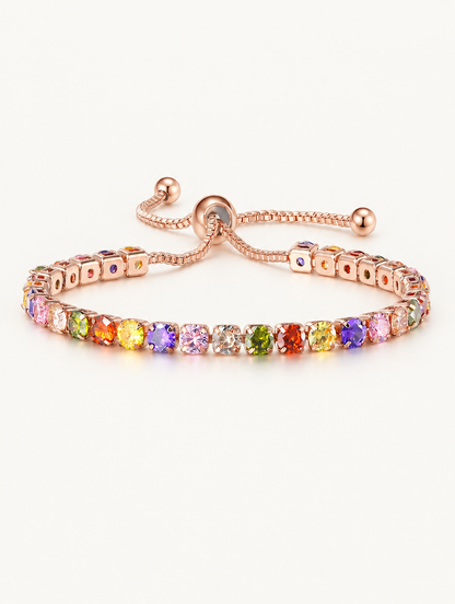 Rose gold slider tennis bracelet with rainbow zirconia stones on a neutral background