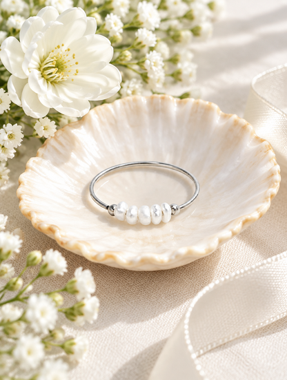 Silver three pearl band ring in a small dish with styling props