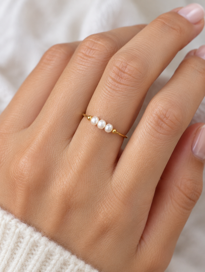Woman wearing a gold three pearl band ring on her finger