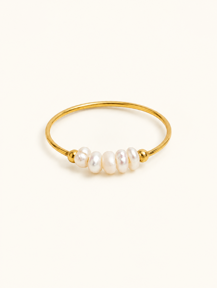 Gold three pearl band ring on a neutral background