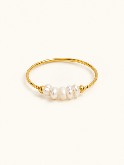 Gold three pearl band ring on a neutral background