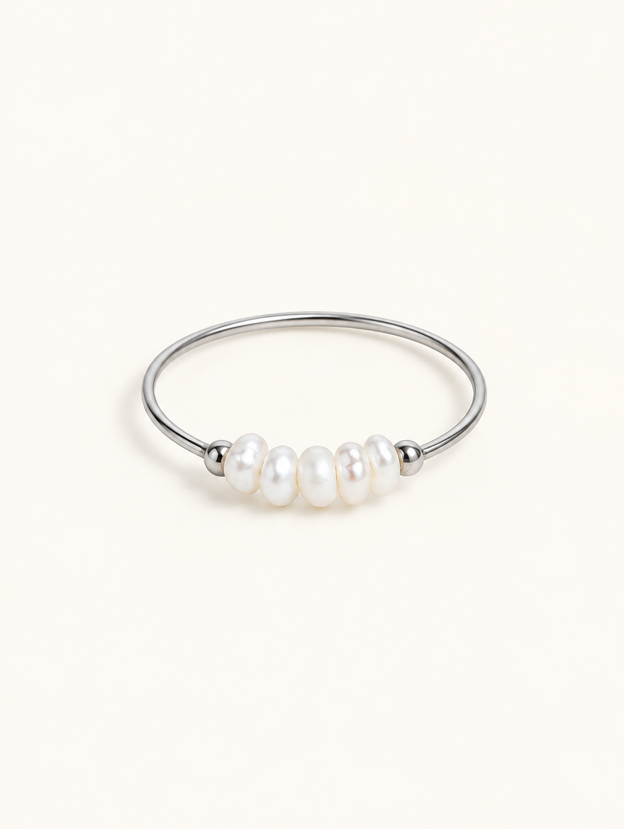 Silver three pearl band ring on a neutral background