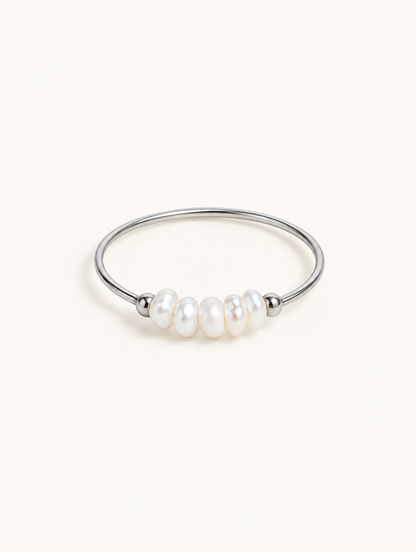 Silver three pearl band ring on a neutral background