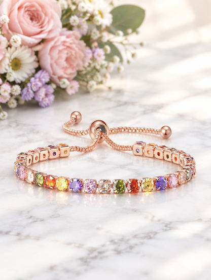 Rose gold rainbow zirconia bracelet beside pastel flowers on marble