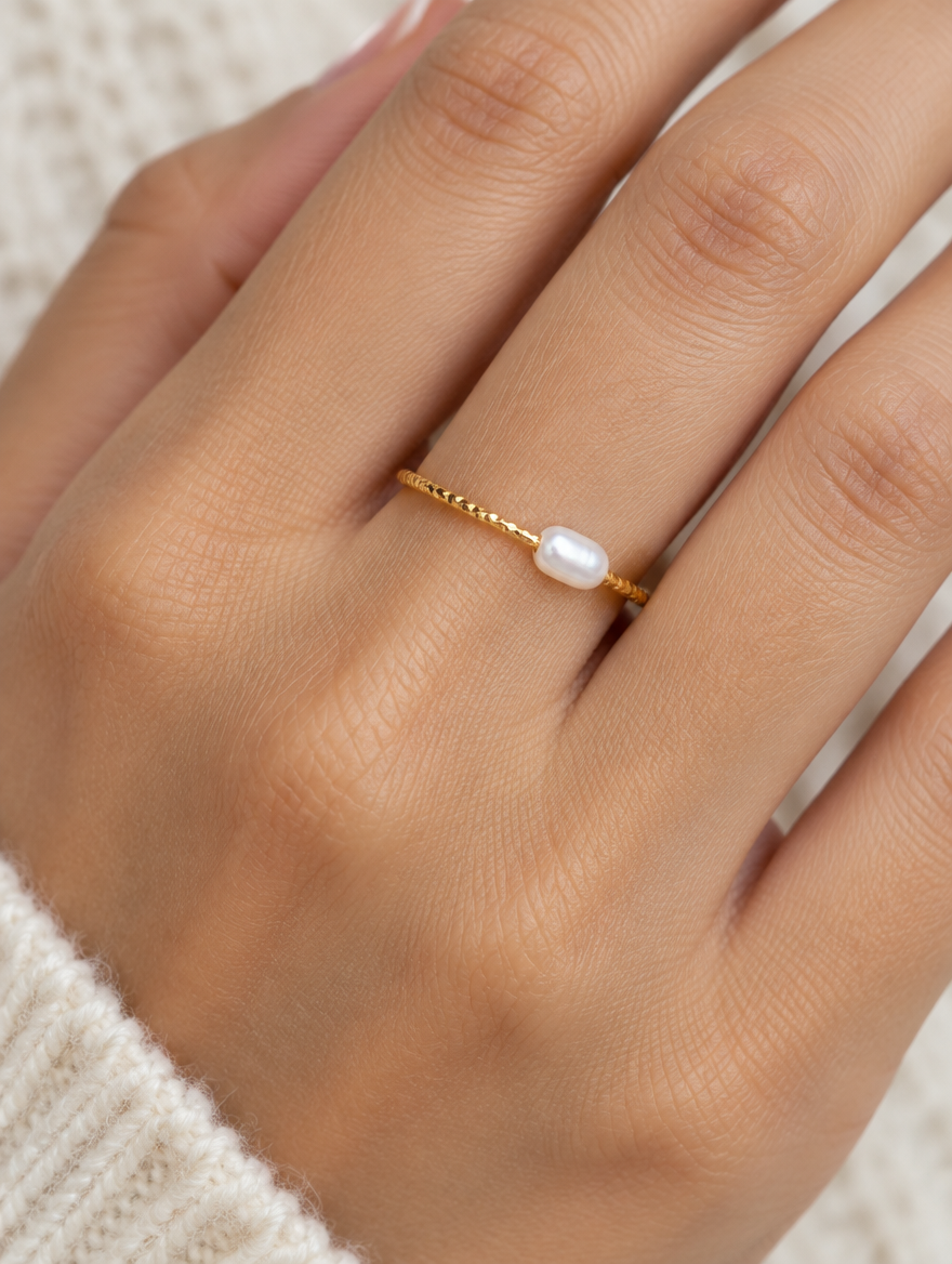 Woman wearing a thin gold twisted band ring with a pearl on her finger