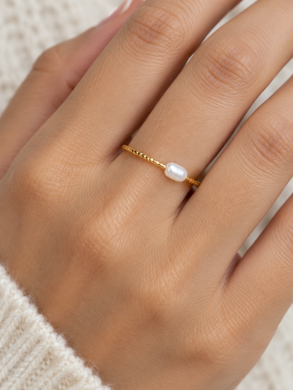 Woman wearing a thin gold twisted band ring with a pearl on her finger