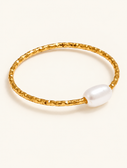 Thin gold twisted band ring with a pearl on a neutral background