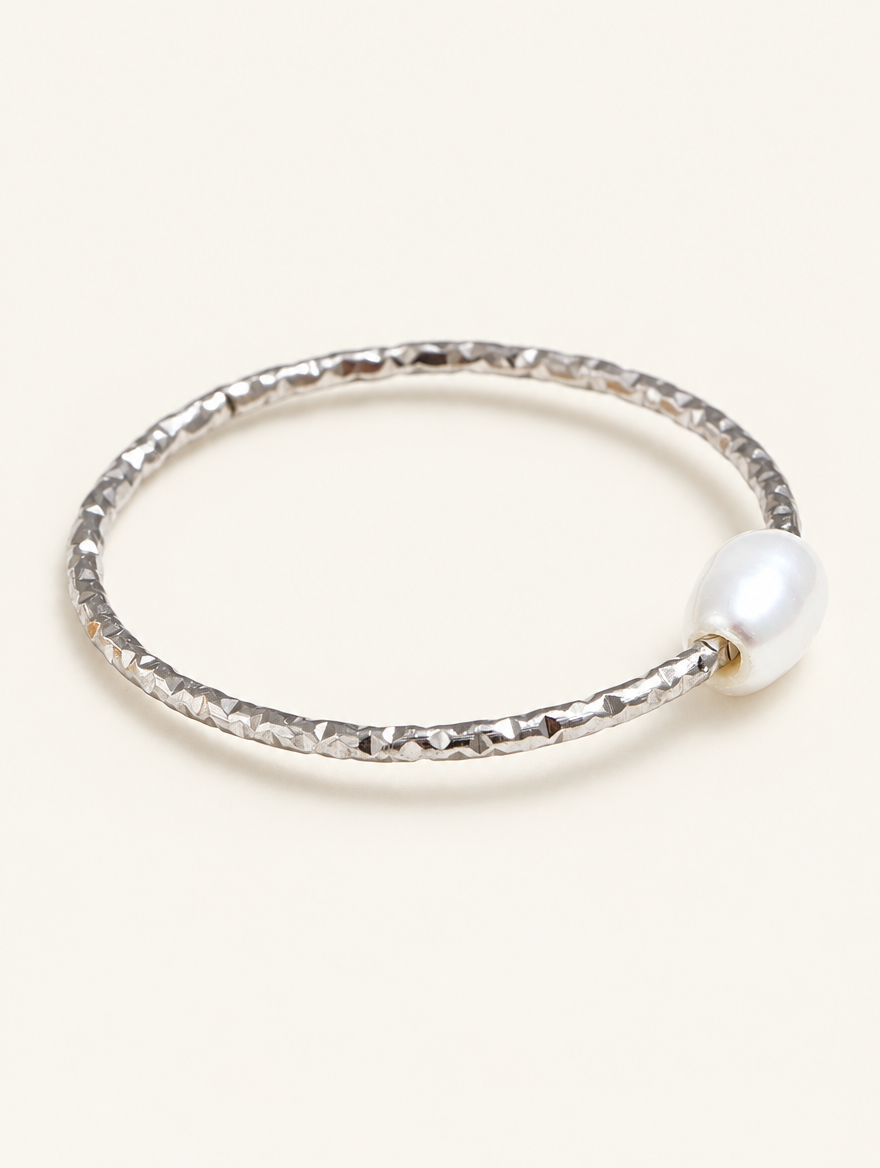 Thin silver twisted band ring with a pearl on a neutral background
