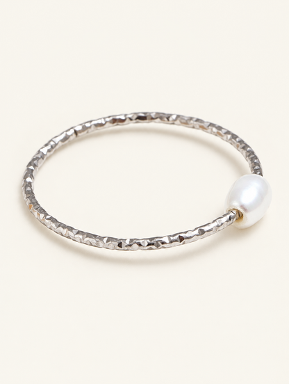 Thin silver twisted band ring with a pearl on a neutral background